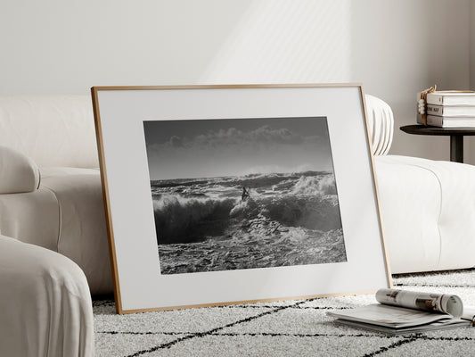 Black and white ocean photo of a surfer silhouette at Hossegor Central Beach, France, during the Quiksilver Festival, with heavy waves, foam texture, and dramatic sky.