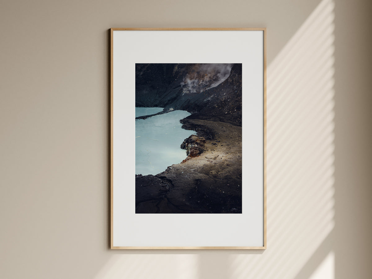 Natural oak framed fine art print of Poas volcano crater hanging on a beige living room wall