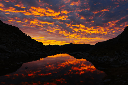 Fine art landscape photograph of a dramatic fiery sunrise reflecting in a mountain lake in the Pyrenees by Basile Tournier