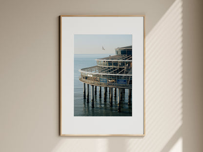 Natural oak framed fine art print of Scheveningen Pier hanging on a neutral living room wall