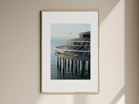 Natural oak framed fine art print of Scheveningen Pier hanging on a neutral living room wall